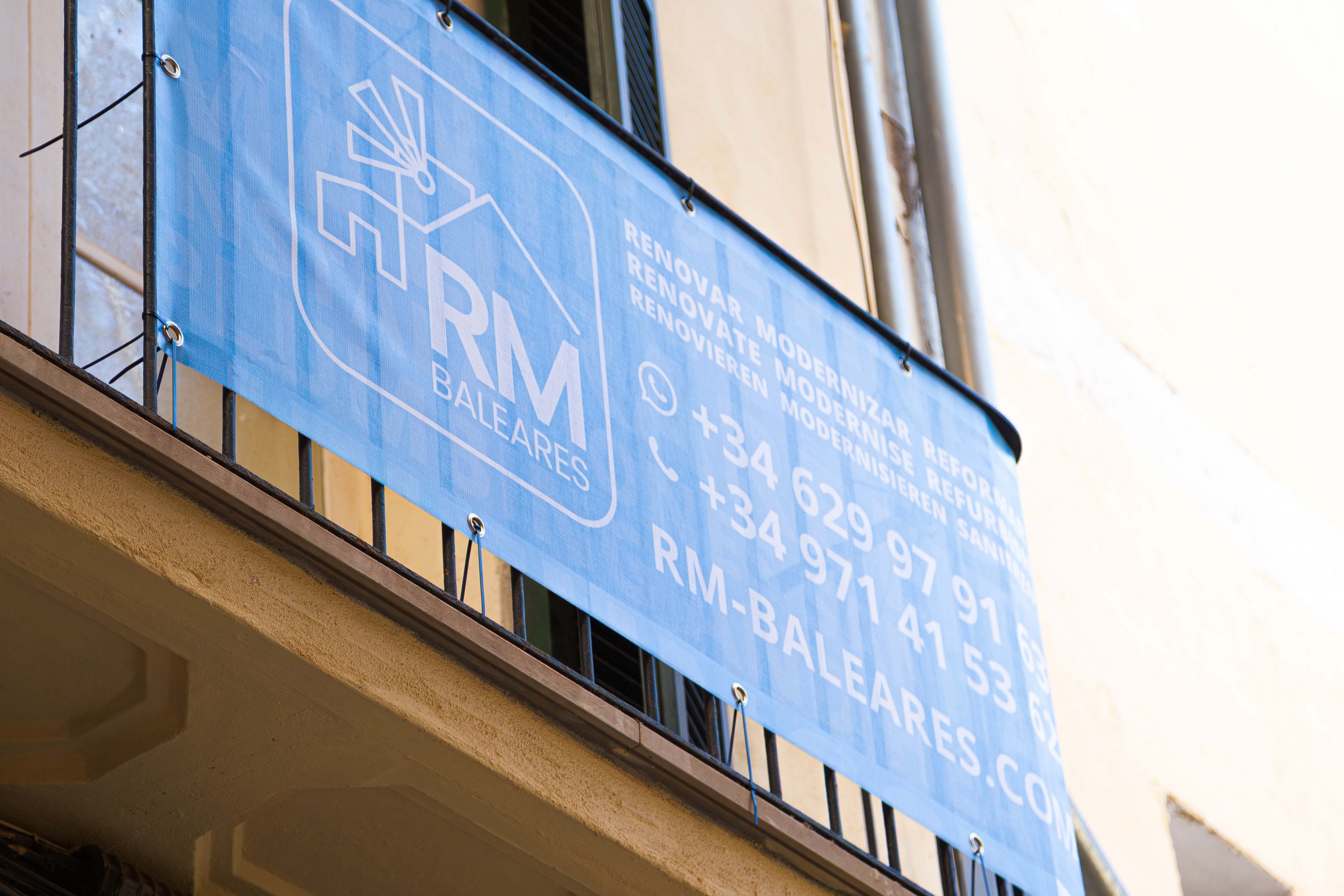 Banner an einem historischen Balkon des Bauunternehmens RM BALEARES auf Mallorca